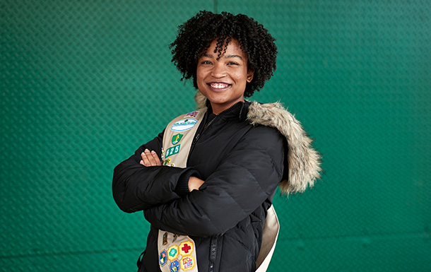 ambassador high school girl scout wearing sash outside against green background
